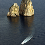 Bateau naviguant près de rochers imposants en mer.
