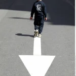 Enfant marchant sur une flèche sur la route