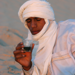 Homme en turban blanc buvant du thé dans le désert
