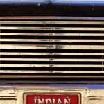 Plaque d'immatriculation rouge avec inscription "Indian and proud of it" sur une grille de voiture