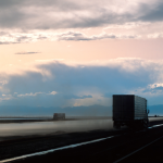 Paysage routier au coucher du soleil avec camions et voitures