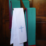 Étole liturgique suspendue devant un panneau en bois