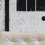 Canapé en cuir beige devant un mur abstrait