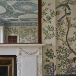 Miroir sur une cheminée blanche avec un fond fleuri et un plafond orné