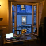 Bureau à domicile avec fenêtre ouverte sur cour parisienne
