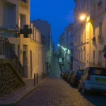 Rue en pente pavée éclairée la nuit