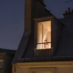 Fenêtre éclairée sur un toit parisien la nuit