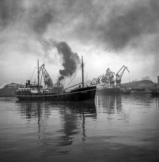 AKG7439656.webp Navire dans un port industriel avec grues et fumée – Image 1