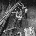 Chargement de barres métalliques par des ouvriers dans un entrepôt industriel