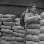 Travailleur Manipulant des Sacs de Ciment sur un Quai Industriel