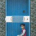 Enfant derrière une porte en fer bleu