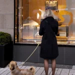 Femme avec chien devant une vitrine de magasin