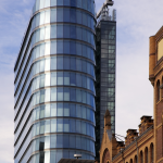 Immeuble moderne en verre à côté d'un bâtiment historique en brique