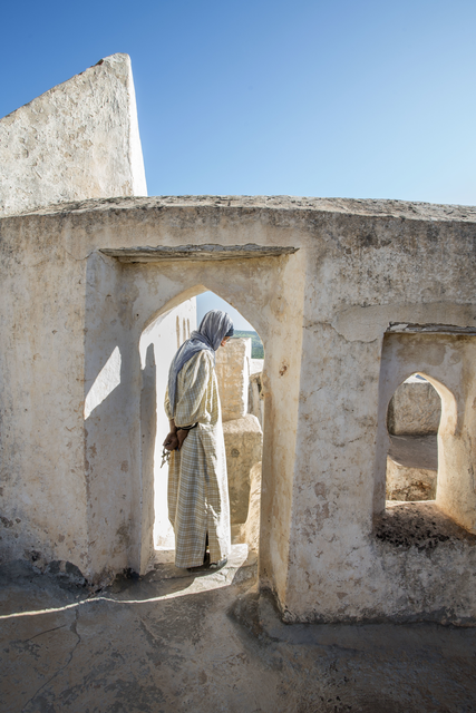 AKG7480592.webp Vieille femme dans un vieil édifice méditerranéen – Image 1