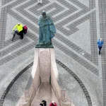 Statue et visiteurs sur une place pavée vue d'en-haut