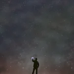 Personne tenant un téléphone sous un ciel étoilé