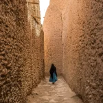 Femme dans une ruelle étroite entre des murs en pierre