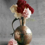 Vase en cuivre avec des oeillets rouges et blancs