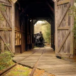 Train à vapeur traversant un pont couvert en bois