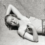 Femme en maillot de bain allongée sur des rochers en plein soleil
