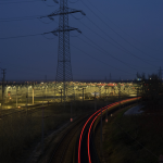 Rails de train lumineux et pylône électrique la nuit