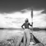Homme naviguant en pirogue sur une rivière tropicale