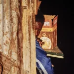 Homme caché derrière une cloison en métal rouillé