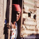 Femme Regardant par la Porte d'une Maison en Tôle