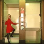 Femme en robe rouge utilisant un ascenseur en intérieur