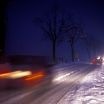 Route enneigée la nuit avec circulation automobile