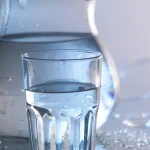 Verre d'eau fraîche avec une carafe en arrière-plan