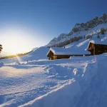 Cabanes enneigées au lever du soleil dans les Alpes