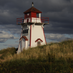 Phare rouge et blanc sous un ciel nuageux