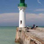 Phare blanc avec pêcheurs sur la jetée
