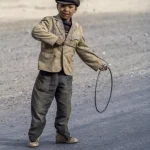 Enfant Jouant avec un Cerceau dans une Rue