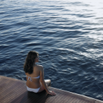 Femme en maillot de bain se relaxant sur un quai au bord de l'eau