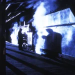 Scène nocturne d'une gare avec une locomotive à vapeur