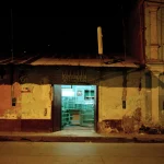 Boutique de vitrerie éclairée la nuit dans une rue délabrée