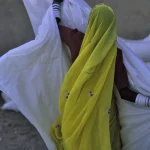 Femme en sari jaune tenant un drap blanc
