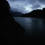 Rivière calme au crépuscule sous un ciel nuageux