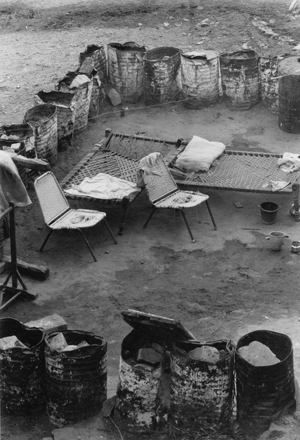 AKG816295.webp Campement de fortune avec des chaises et des lits – Image 1