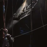 Travailleurs sur une passerelle dans un chantier naval sombre