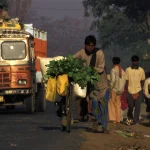 Marchand de légumes poussant un vélo sur une route animée en Inde