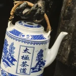 Main tenant une théière asiatique en porcelaine bleue et blanche