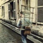 Homme transportant des vitres dans une ruelle européenne