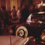 Scène nocturne avec voitures classiques et foule