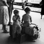 Enfants attendant à la gare avec des bagages.