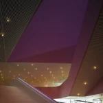 Escalier moderne sous un plafond géométrique illuminé