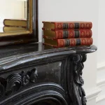 Livres anciens empilés sur cheminée en marbre noir