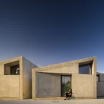Femme assise devant une maison moderne en béton